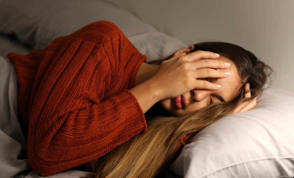 5 Things To Do To Ensure a Great Night's Sleep 2 Young woman has a difficulty falling asleep because of lights.