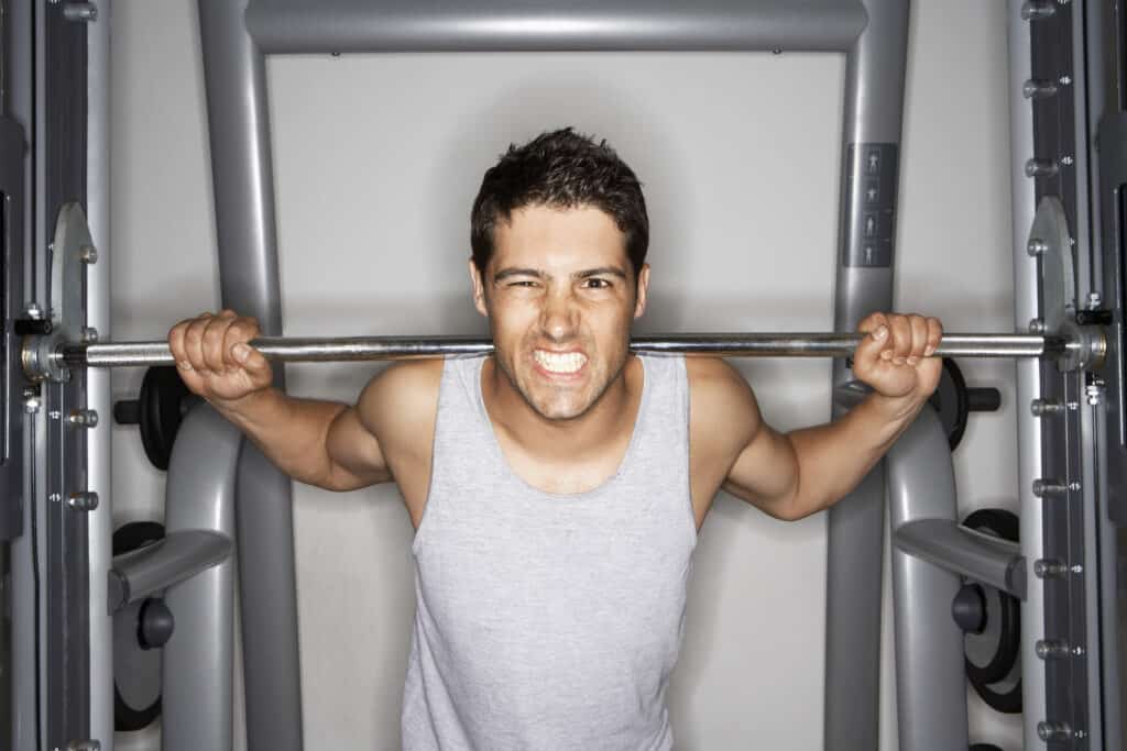 Man grimacing lifting weights