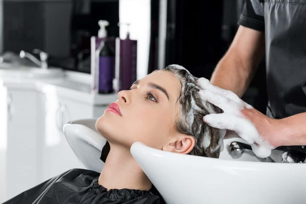 Hairdresser washing hair with shampoo